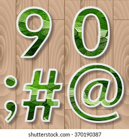 Modern alphabet with shadow effect.Green Leaves font on a wood background.9,0,octothorpe, number,digits pound, sharp, hash,semicolon,at or at symbol