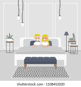 Modern bedroom interior. Couple of young caucasian adults lying in the double bed. Scandinavian design.