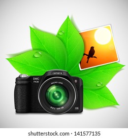 Modern photo camera with green leaves for  your summer design. Vector illustration.