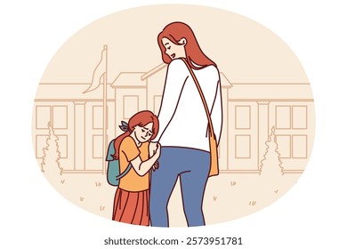 Mom accompanies daughter in elementary school, supporting or motivating girl standing near building of educational institution. Little girl feels attached to mother and does not want to go in school