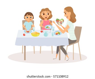 Mom and child eating meal around kitchen table. Happy mother and her two kids sitting eating healthy lunch in home. Smiling woman feeds her daughter and son