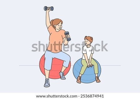 Mom and daughter do fitness sitting on fitballs and lifting dumbbells to improve health. Woman sets example for child, wanting to teach girl to regularly engage in fitness or sports.