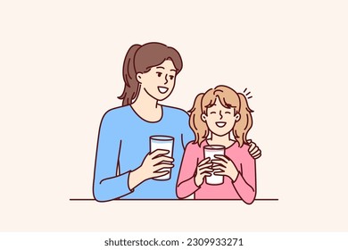 Mom and daughter drink natural milk to get useful vitamins and lactose or calcium from eco product. Woman hugging smiling teenage girl drinking milk to promote healthy food without chemicals