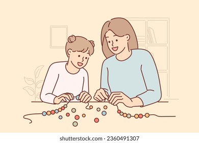 Mamá e hija juntos hacen pulsera de cuentas DIY para hacer realidad la creatividad de los niños. La mujer enseña a las niñas a crear joyas para crear un aspecto de moda o vender cuentas hechas a mano.