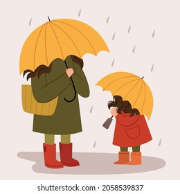 Mom and daughter with yellow umbrellas walk in the rain. Autumn walk. Family day.