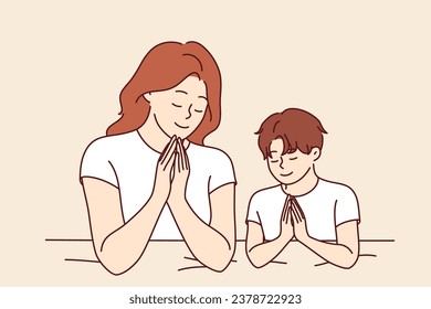 Mamá reza con su hijo antes de la cama, pidiendo a Dios que salve de los problemas y enseñando a los niños un estilo de vida religioso. Mujer y niño rezando haciendo gestos de oración y cerrando los ojos para pedir ayuda a Dios