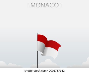 Monaco's flag flutters on a pole that stands tall against a white sky