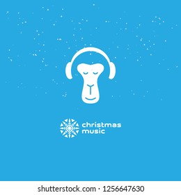 Monkey enjoys the Christmas music. Relaxing monkey in headphones. Logotype with snowflake.
