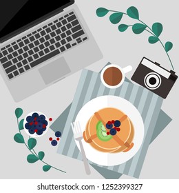 Morning pancake with berries and syrup and coffee serve on table next to laptop