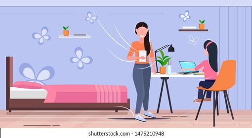 mother and daughter using digital gadgets at workplace woman helping her child to do homework modern living room interior flat full length horizontal