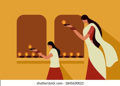 A mother and daughter wearing traditional dress holding lighted Diwali oil lamps in their hands.Concept for Diwali festival in India