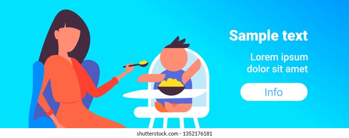 mother feeds her little son with spoon baby sitting in high eating chair child feeding childcare concept portrait copy space blue background horizontal flat