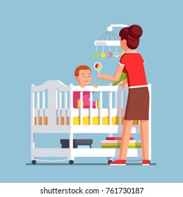 Mother playing rattle to little baby son toddler sitting in crib bed or cot. Woman babysitter looking after newborn boy. Mom and child in kids room. Family childcare. Flat cartoon vector illustration.