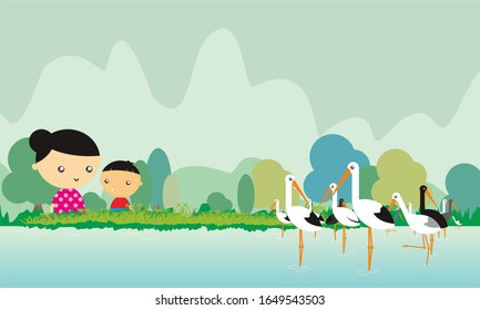 mother and son looking at herons in a marsh