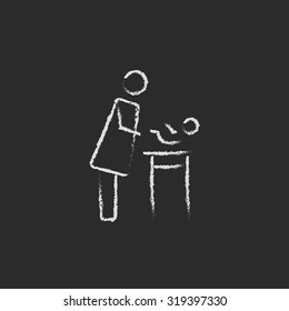 Mother taking care of baby hand drawn in chalk on a blackboard vector white icon isolated on a black background.