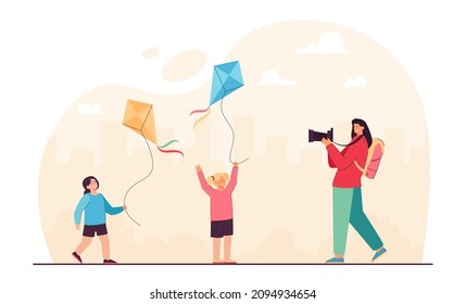 Mother taking picture of daughters playing game with kites. Woman holding photo camera flat vector illustration. Summer adventure, vacation concept for banner, website design or landing web page