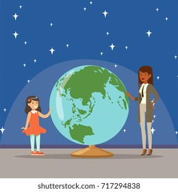 Mother telling her daughter about earth planet at the planetarium