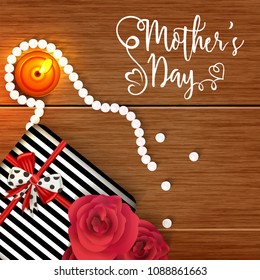 Mother's Day celebration concept with gift box, roses, pearls and candles on woodle background.