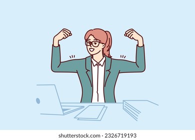 Motivated businesswoman showing biceps on hands sitting at office table with laptop and demonstrating ambition. Motivated woman manager is ready to start work and strive for career achievements