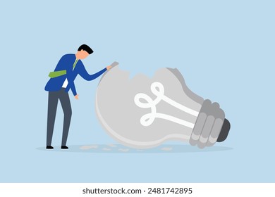 motivation after business failure, depressed businessman standing with old broken light bulb idea that failed miserably.