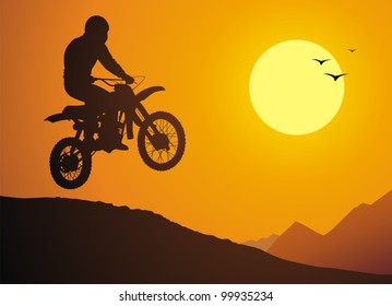 The motorcyclist does a jump against a sunset