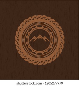 mountain icon inside badge with wood background