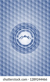 mountain icon inside blue emblem or badge with abstract geometric pattern background.