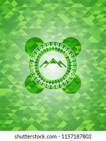 mountain icon inside green emblem with mosaic background