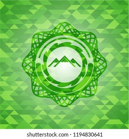 mountain icon inside green emblem with triangle mosaic background