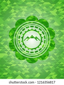 mountain icon inside green emblem. Mosaic background