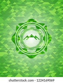 mountain icon inside green emblem with triangle mosaic background