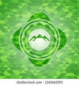 mountain icon inside green emblem with mosaic background