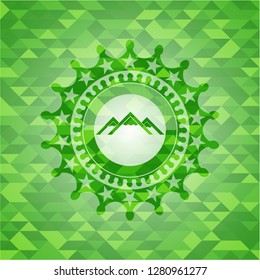 mountain icon inside green emblem with triangle mosaic background