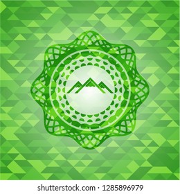 mountain icon inside green emblem with mosaic background