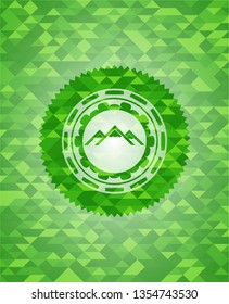 mountain icon inside green emblem with mosaic background