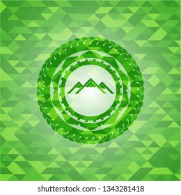 mountain icon inside green mosaic emblem
