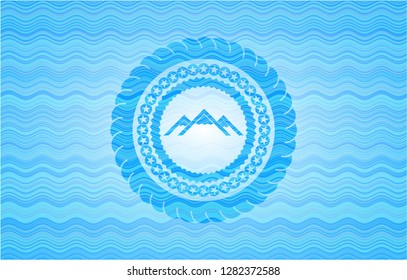 mountain icon inside light blue water wave badge background.