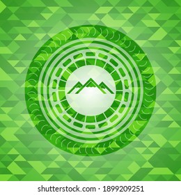 icono de montaña dentro de un emblema verde realista. Fondo mosaico. 