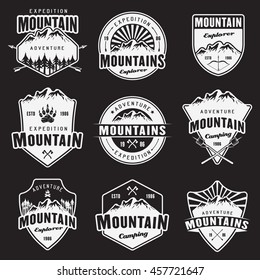 Mountain travel, outdoor adventure, camping and hiking set of white vector emblems, labels, badges and logos isolated on dark background. Recreation and leisure design elements