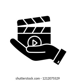 Movie release glyph icon. Video production. Cinematography. Hand holding clapperboard. Film director. Silhouette symbol. Negative space. Vector isolated illustration