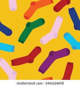 Multi-colored socks on a yellow background seamless pattern. View from above. Many different socks for cold seasons. Socks are scattered on a bright background. 