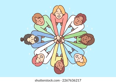 Multiracial people stand in circle with hands outstretched to demonstrate friendship. Men and women look up demonstrating multiracial diversity and national tolerance