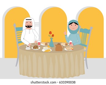 Muslim Arab couple at a dinner table in their home gathered at if-tar feast - table full of delicious traditional Arabic food - ready to break their fast