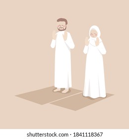 Muslim couple raises hands to do takbirat al ihram in prayer, praying together in position on the prayer mat