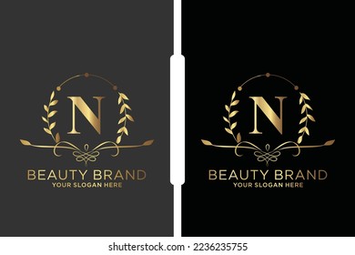 N Logo inicial del vector de belleza, letras doradas florales con hojas de flores y manchas doradas aisladas en fondo blanco. Ilustración vectorial para boda, tarjetas de felicitación, diseño de plantillas de invitaciones