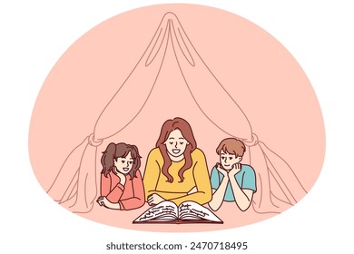 Nanny and two small children reading book lying on floor in tent enjoying fairy tale story. Mom spends time with pre-adolescent children and gets positive emotions from self-parenting