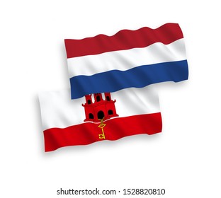 National vector fabric wave flags of Gibraltar and Netherlands isolated on white background. 1 to 2 proportion.