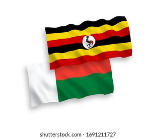 National vector fabric wave flags of Madagascar and Uganda isolated on white background. 1 to 2 proportion.