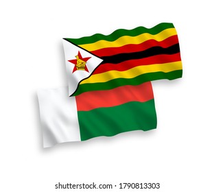 National vector fabric wave flags of Zimbabwe and Madagascar isolated on white background. 1 to 2 proportion.
