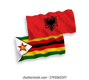 National vector fabric wave flags of Zimbabwe and Albania isolated on white background. 1 to 2 proportion.